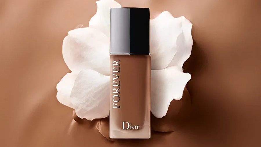 Fondotinta Dior Forever su sfondo marrone con fiore bianco