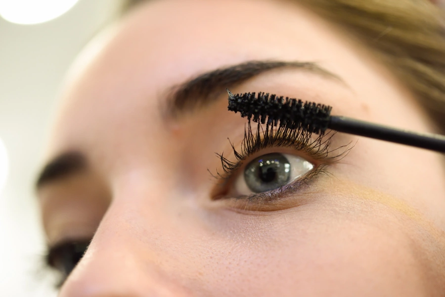 Applicazione del mascara sulle ciglia con scovolino in primo piano